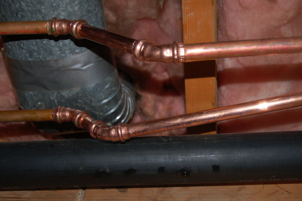 Copper pipe fittings run through a wall cavity