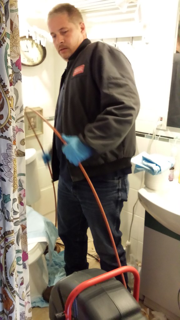 Plumber clearing a blocked drain with a drain auger