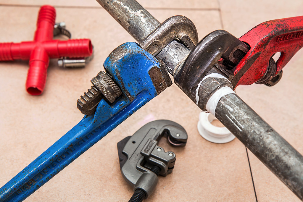 Pipe wrenches and a tube cutter set out on the job
