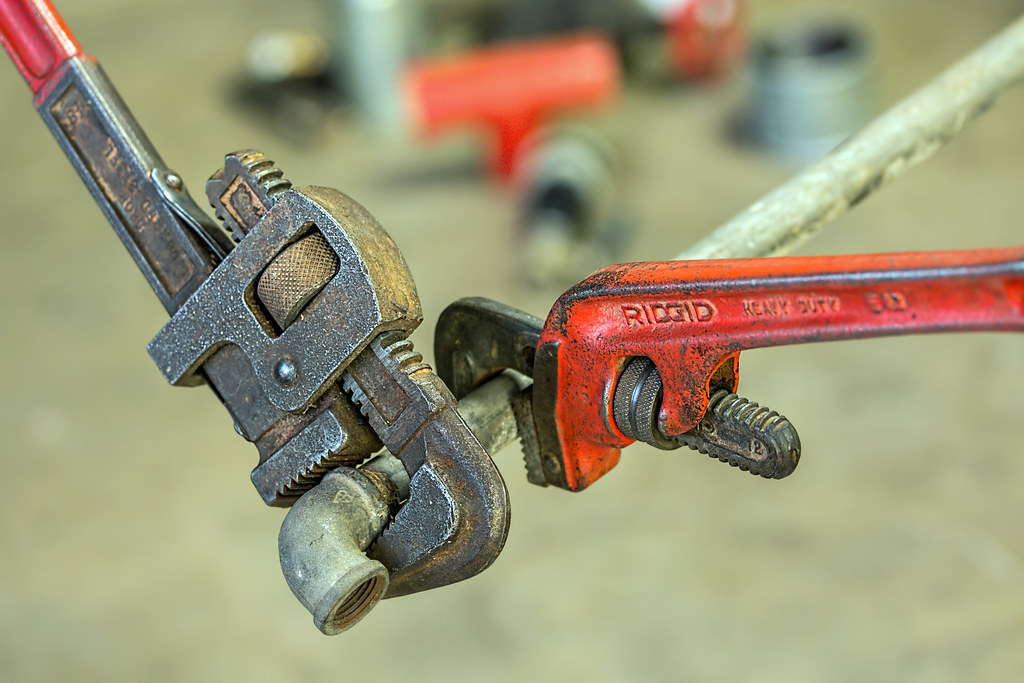 Pipe wrenches gripping a plumbing fitting on a job